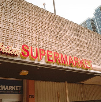 Supermarket sign on a building facade with text and branding.